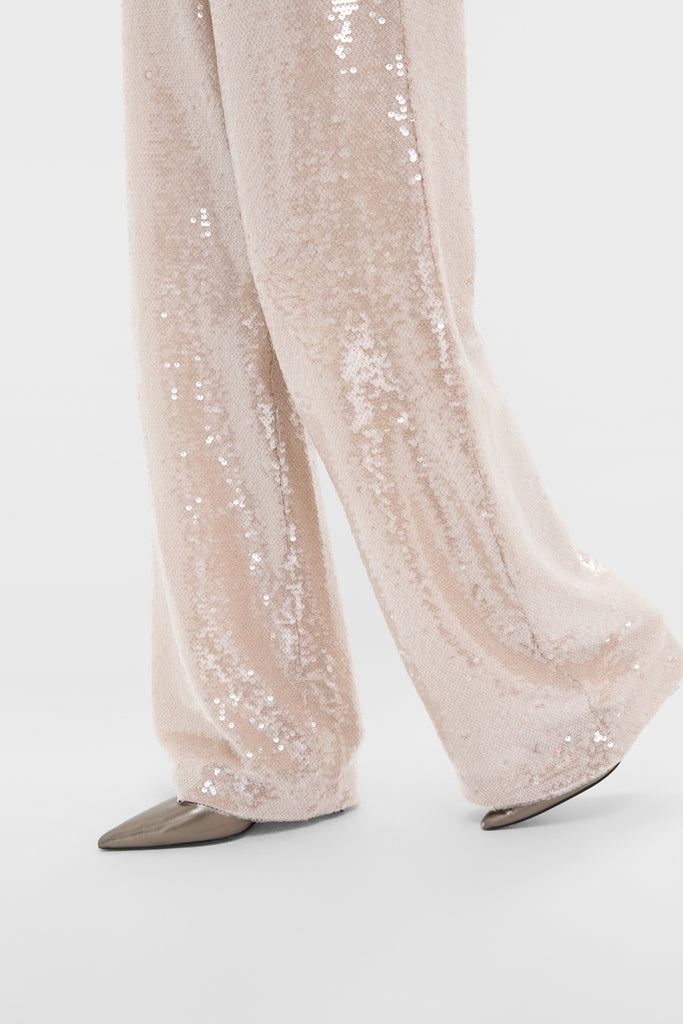 Champagne Sequin Tatum Pants: Classic, effortless high-rise, wide-leg trousers with all-over sequins, peeking taupe shoes, embodying a fun, high-end style for cocktail occasions.