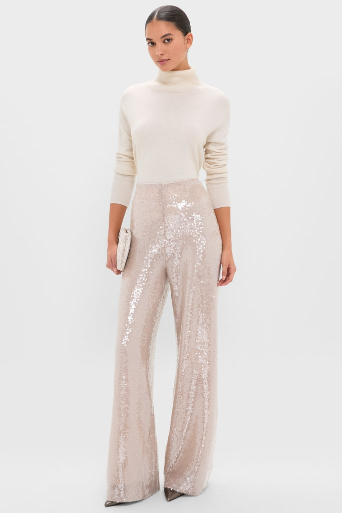 Model wearing classic Champagne Sequin Tatum Pants, high-rise and wide-leg, paired with a cream turtleneck sweater, exuding an effortless, fun, and high-end style.