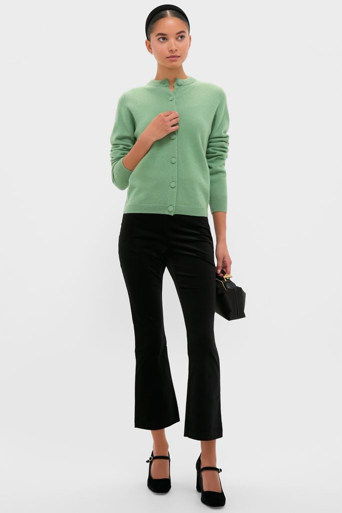 Woman models the classic, high-end Meadow Green Cashmere Covered Button Quinn Cardigan with effortless style, paired with fitted cropped-flare trousers and Mary-Jane block-heel shoes.