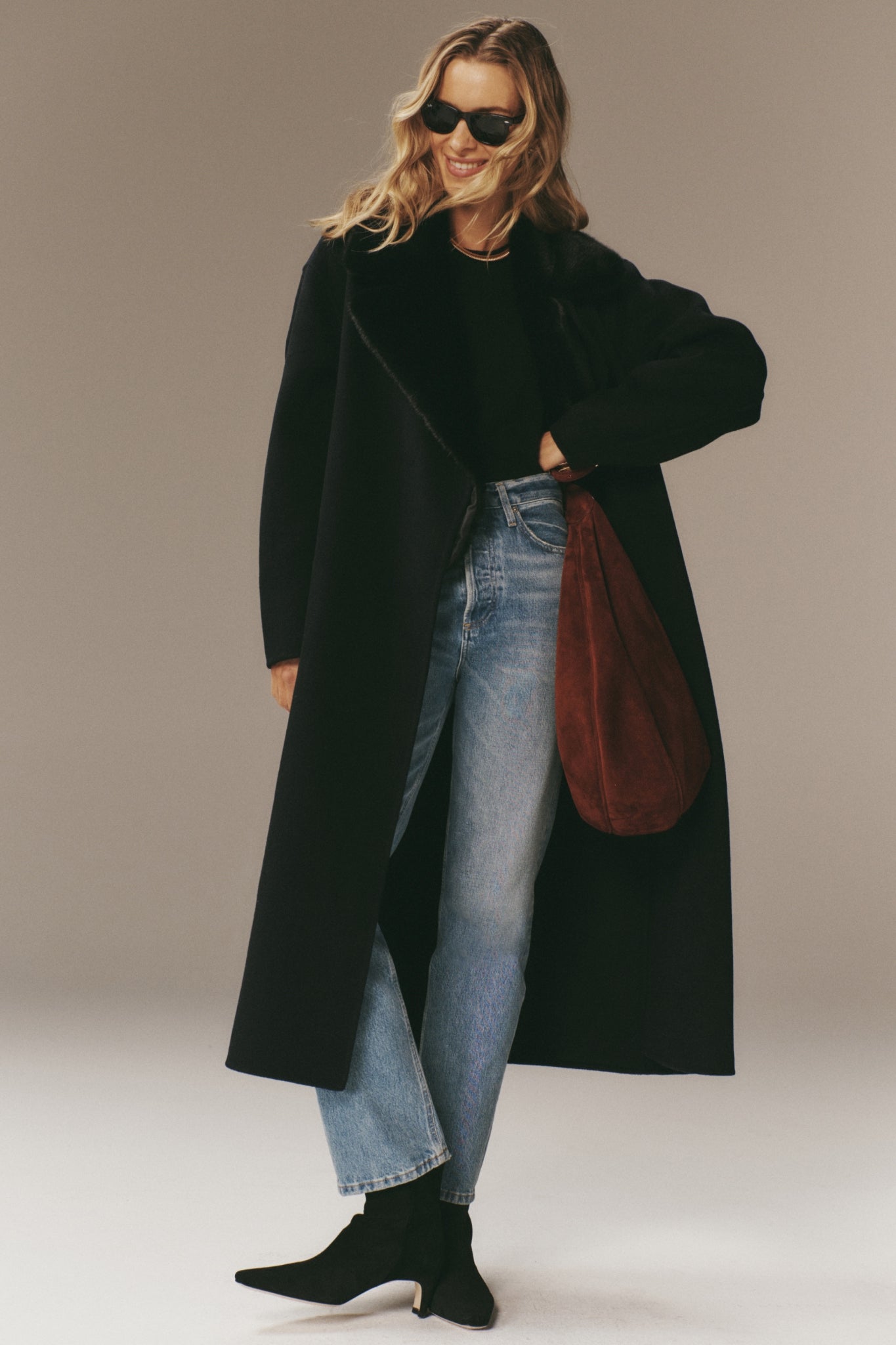 Woman models the classic Navy Wool Trinity Coat, effortlessly styled with straight-leg jeans and suede ankle boots, showcasing high-end, fun, and modern elegance.