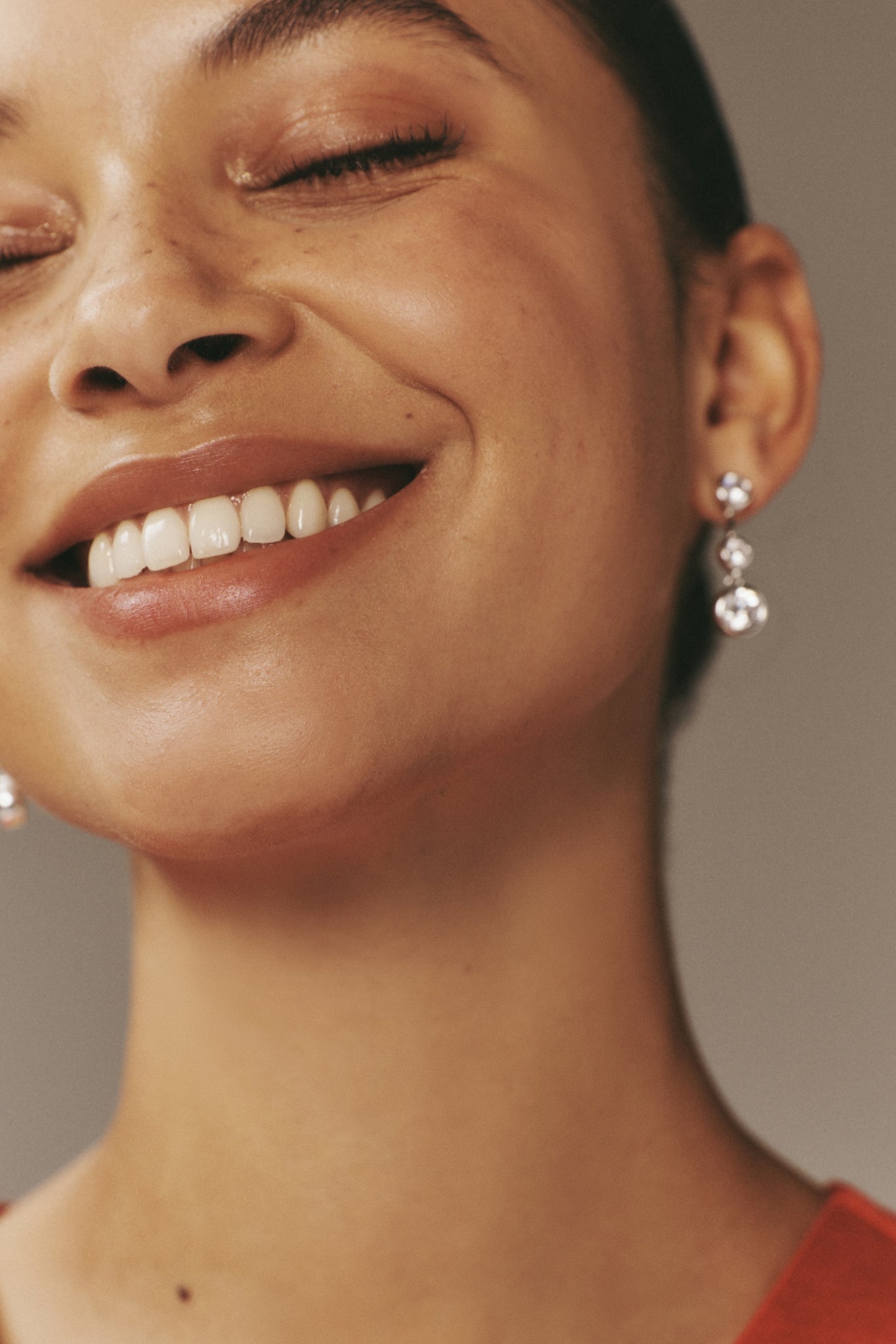 Young woman smiling, showcasing classic, high-end Silver Bezel Jolie Earrings in a modern design, highlighting effortless style and fun sophistication.