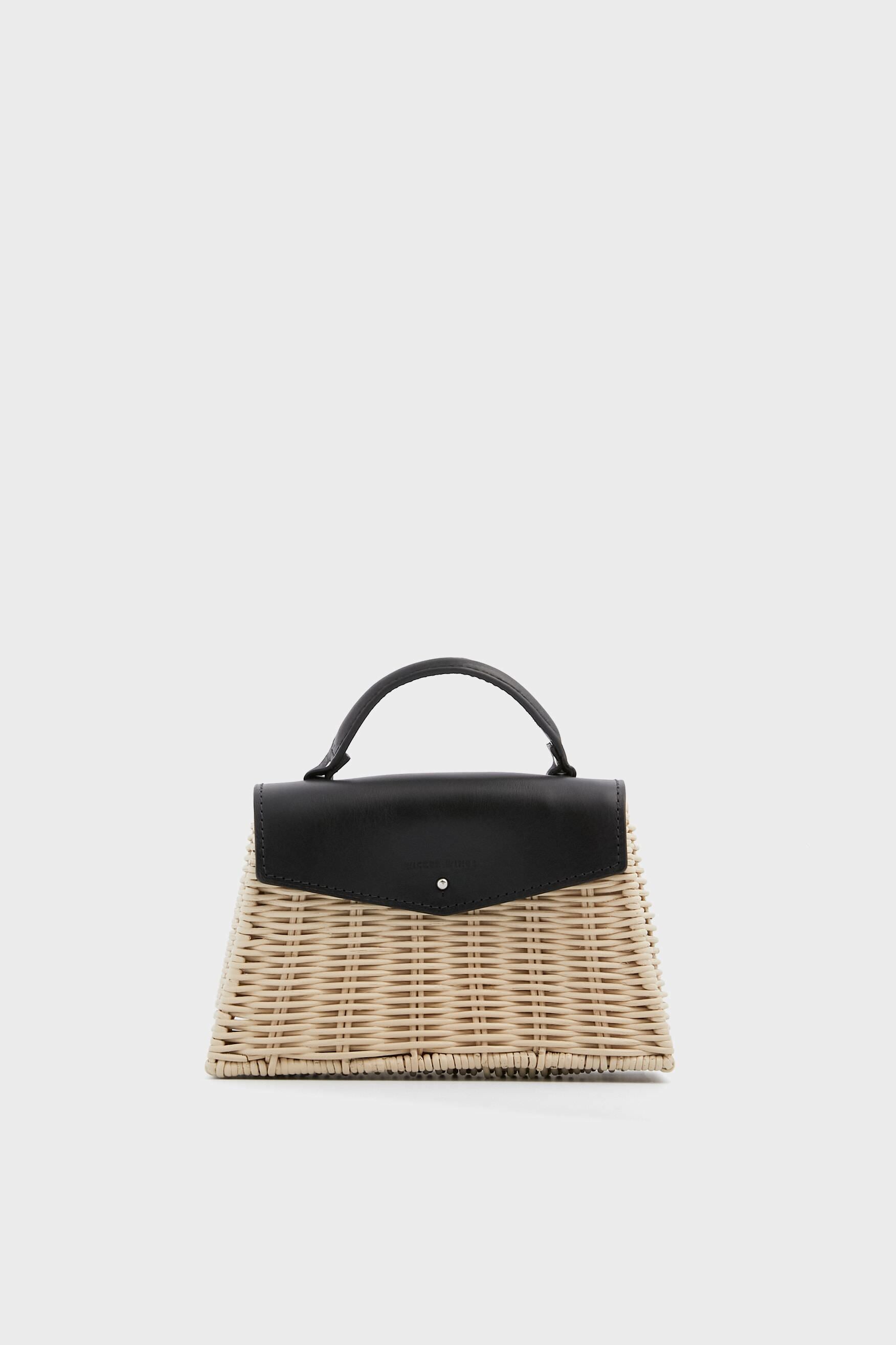 The Wicker Wings bag is a small, structured woven wicker design with a black leather flap and top handle, blending classic elegance with sustainable fashion.