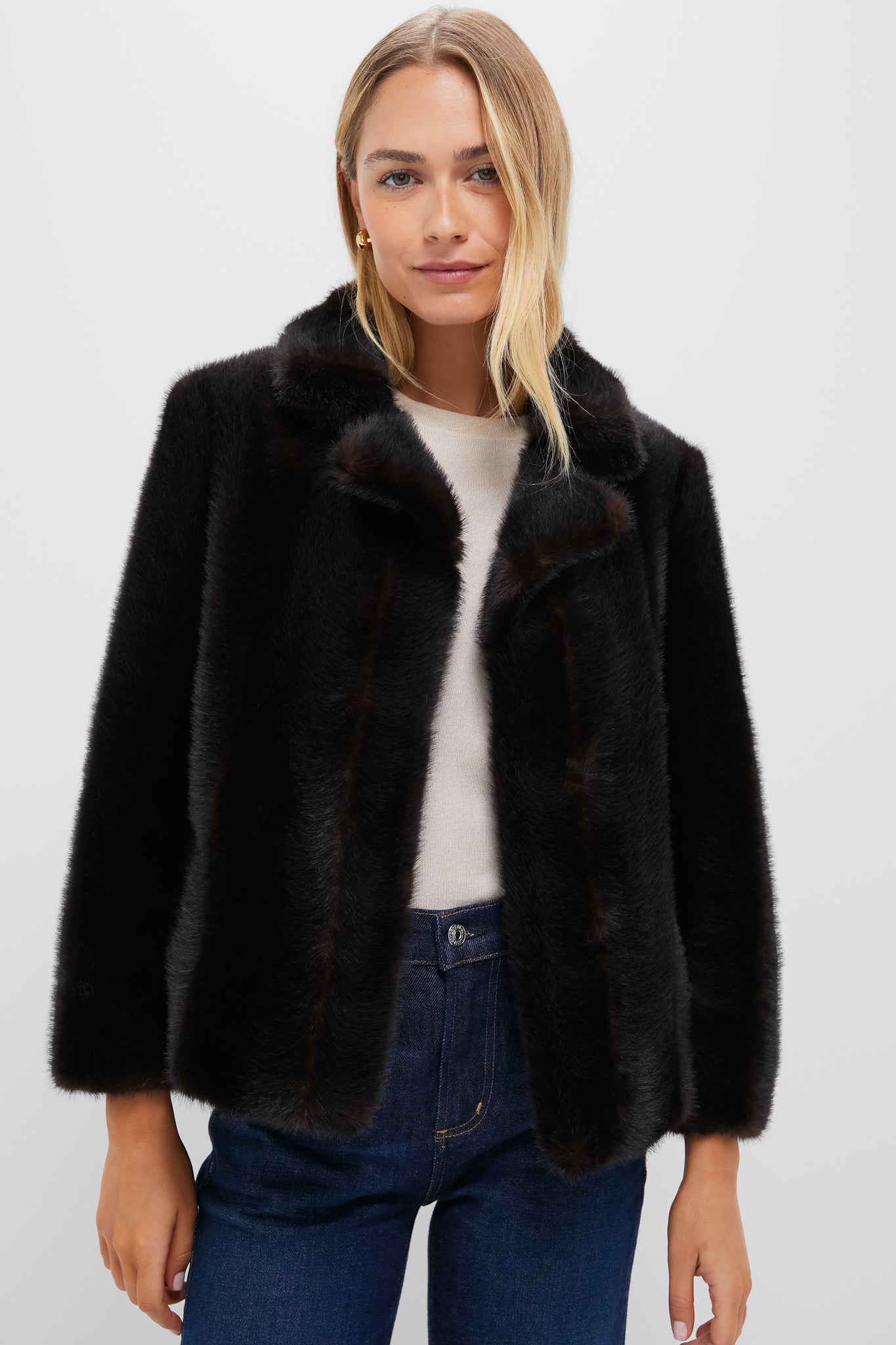 A woman models a Metrobazaarstore dark faux fur coat layered over a light top and blue jeans, posing against a plain white background.