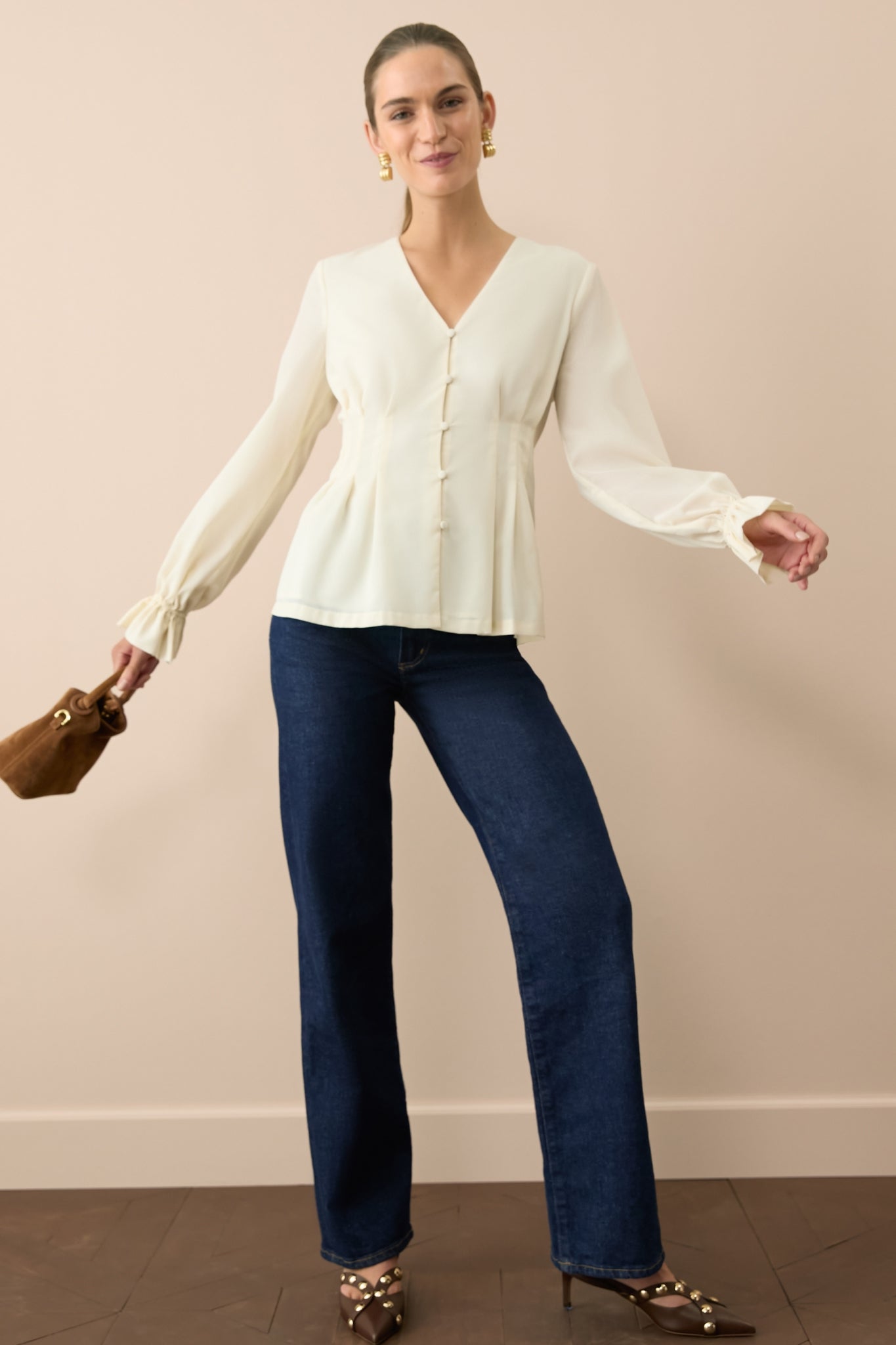 Woman in a pair of dark-wash jeans and a cream long-sleeved top. 