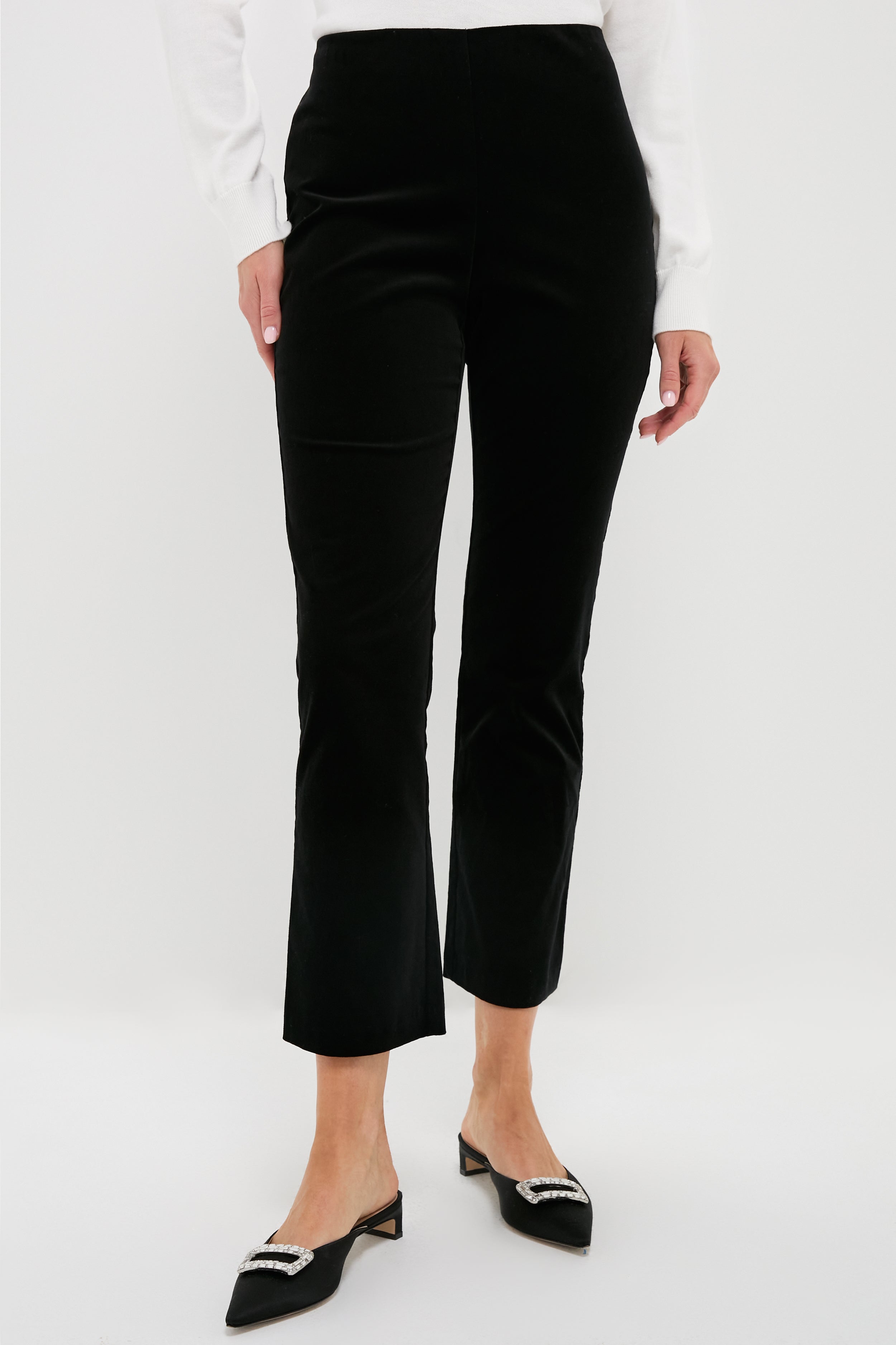 A person wearing Metrobazaarstore black velvet high-rise trousers, black embellished pointed-toe slingback shoes, and a Metrobazaarstore white long-sleeve top.