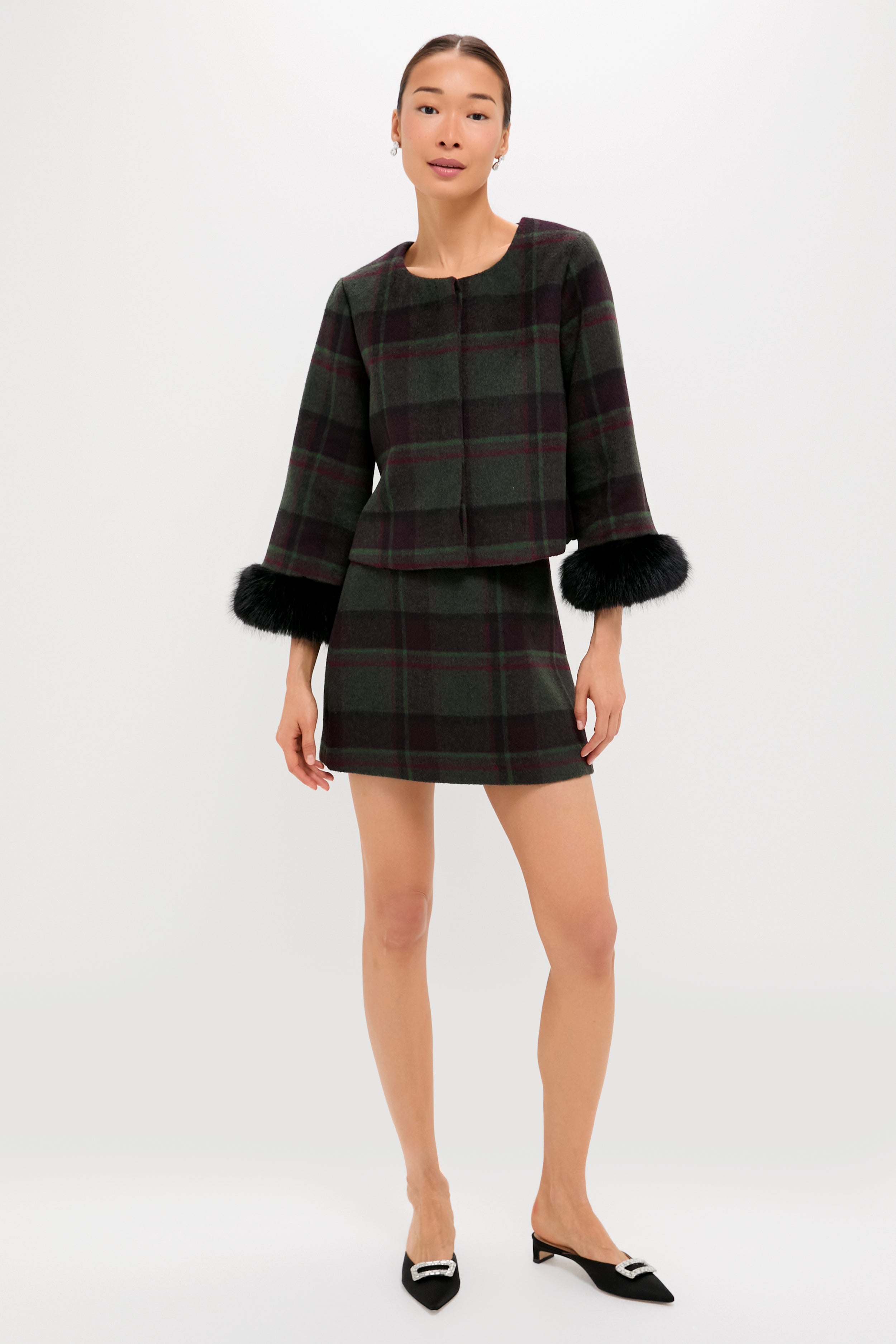 A woman wears a Metrobazaarstore dark plaid jacket with black fur cuffs and a matching wool mini skirt, styled with black pointed-toe flats—a chic transitional wardrobe piece.