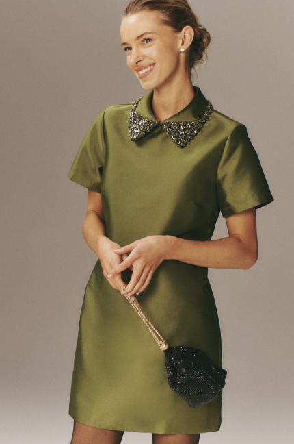 Woman in a green mini dress with jewels on the collar. 