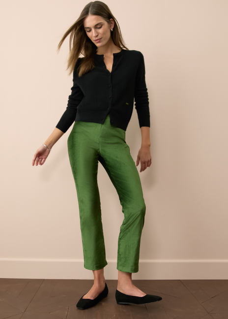 Woman standing in a black cardigan and green velvet pants. 