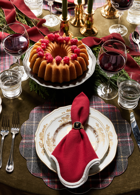 Table set with a red napkin, plaid placemats, and wine glasses. 