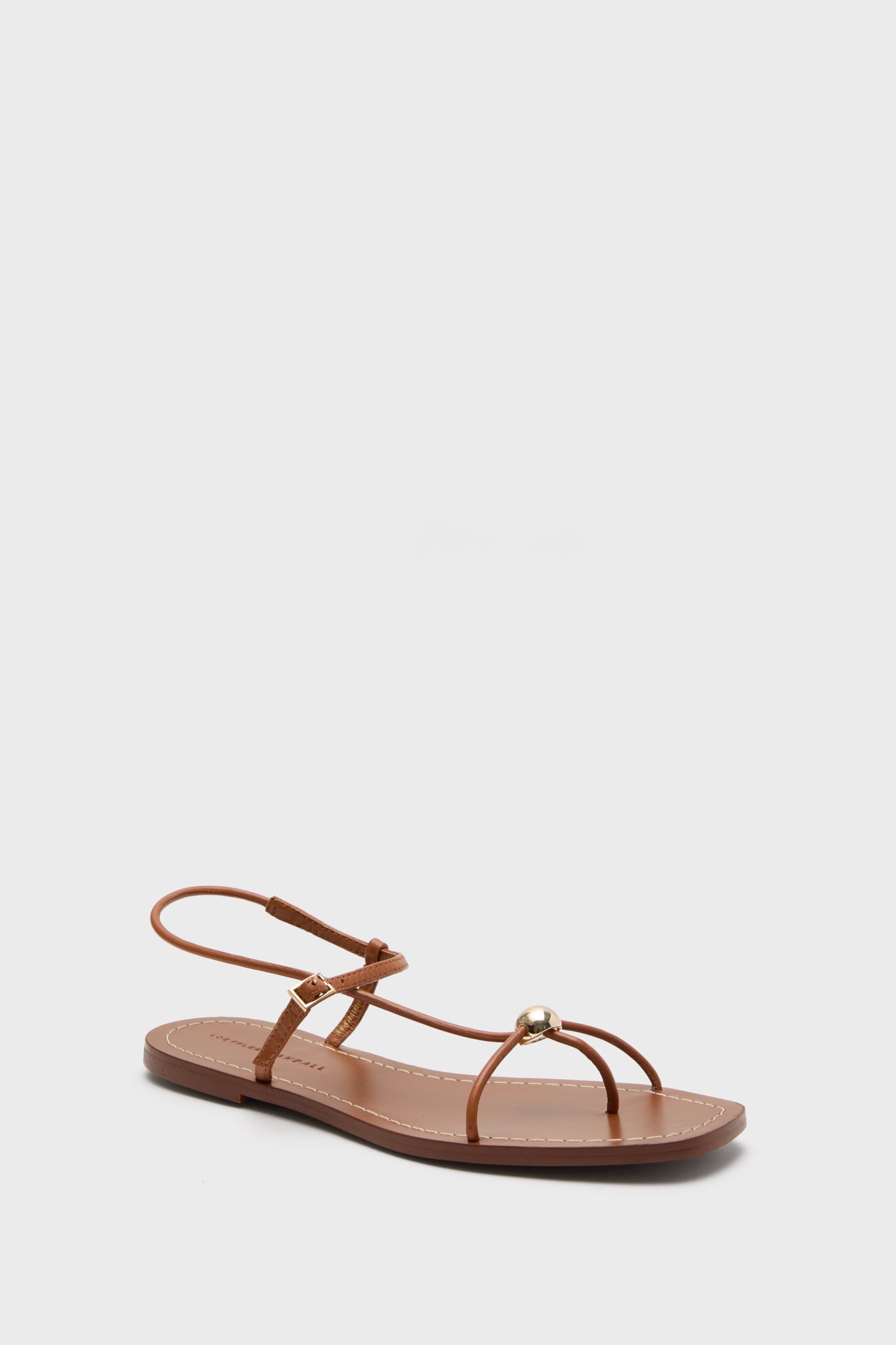 Loeffler Randall brown flat Timber Lara Sandals feature thin straps, a gold ball detail, and an ankle buckle.