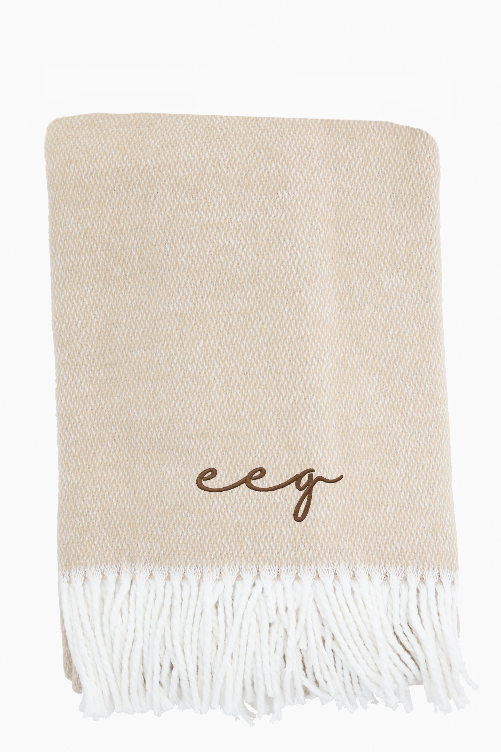The Matouk beige brushed cotton throw features white fringed edges and brown "eeg" embroidered initials for a touch of luxury.