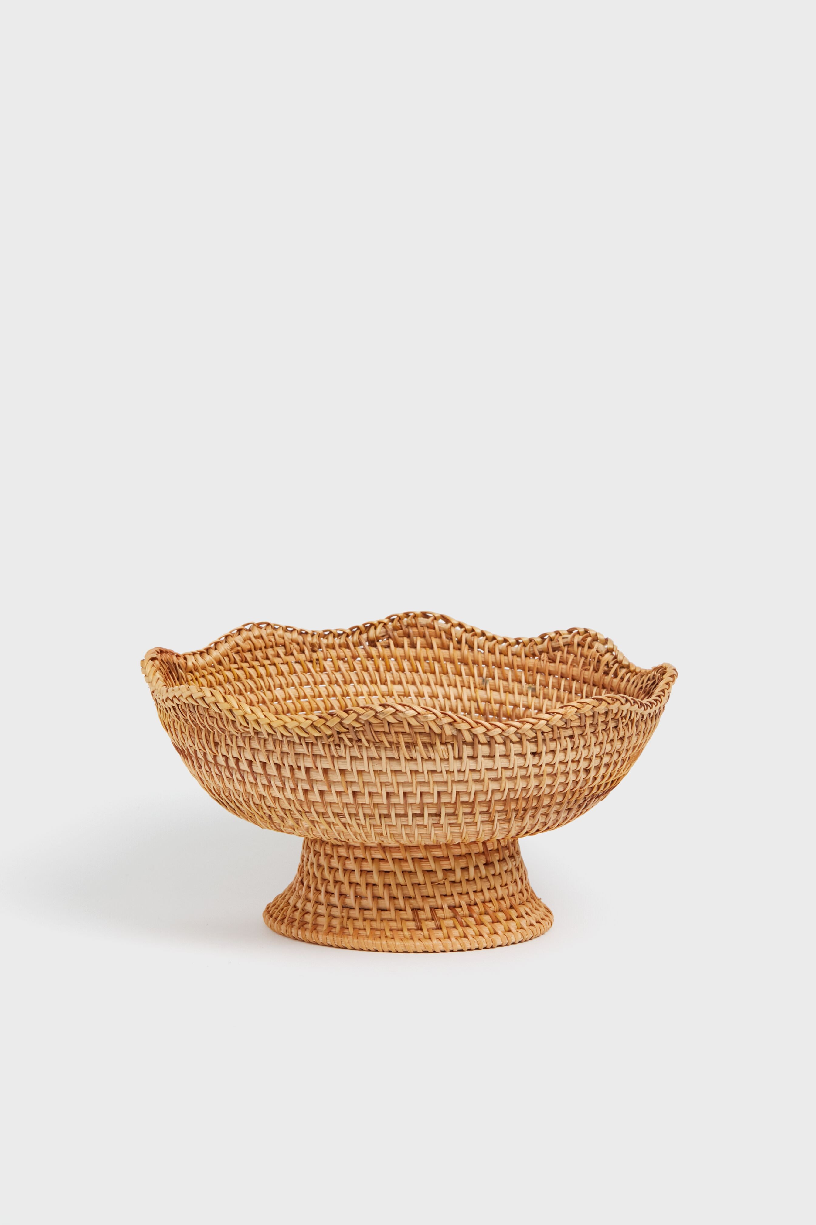 The Metrobazaarstore Home woven bowl features a wide, flared base and scalloped rim, inspired by classic rattan footed bowls—ideal as a decorative accent for your kitchen.