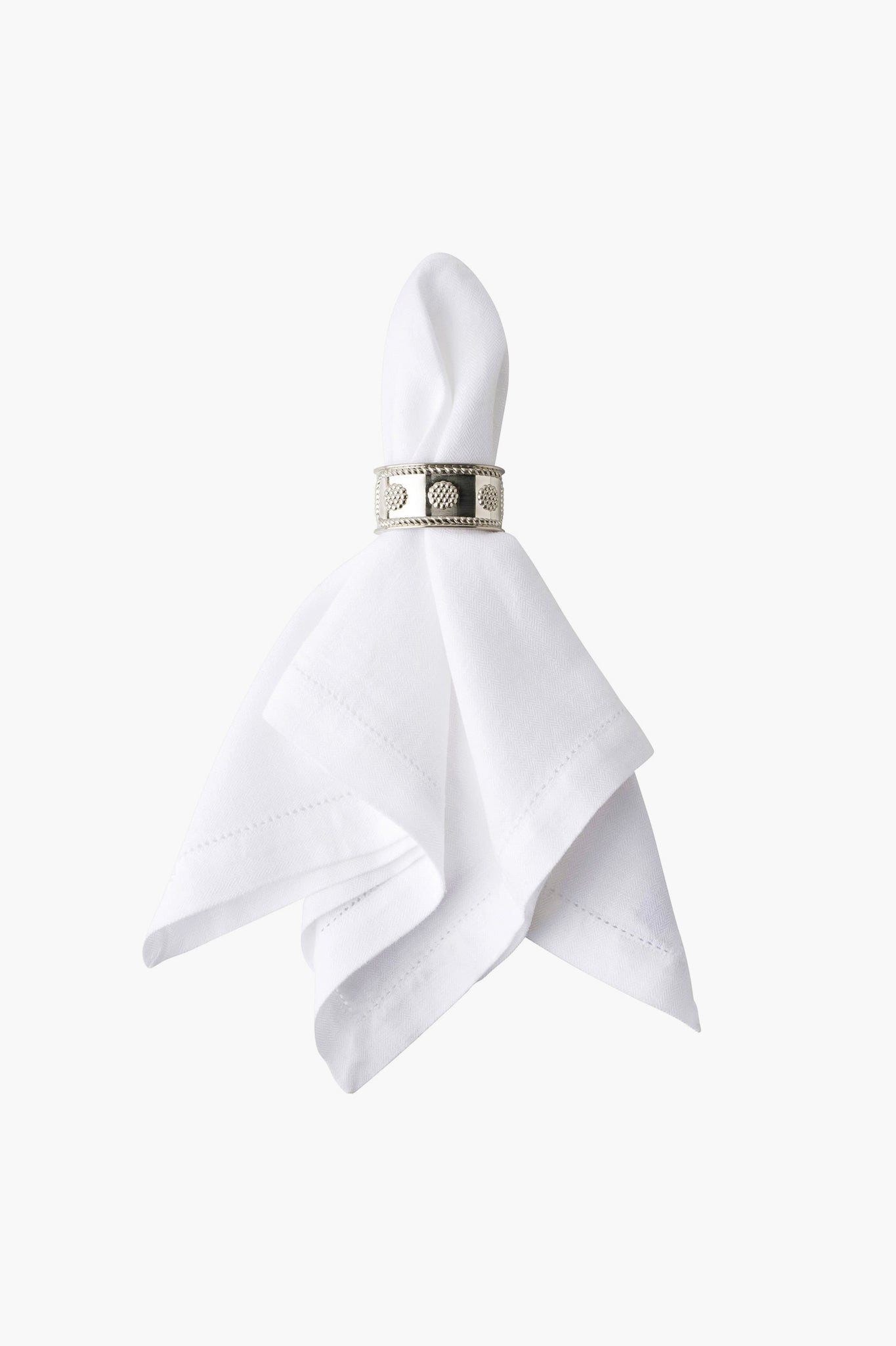 A white cloth napkin folded through a silver Juliska brand napkin ring brings an elegant touch to your table setting.